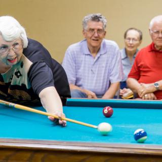 A group of seniors enjoying a game of billiards.