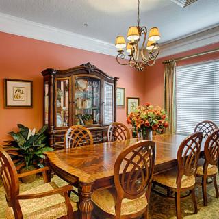 A warm and elegant dining room with a wooden table, chairs, and a chandelier.