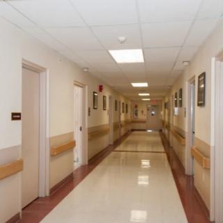 An empty hospital corridor with clean floors and closed doors.