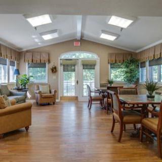 A spacious and well-lit living area with comfortable seating, tables, and ample natural light streaming through the windows.