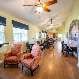 A spacious living room with comfortable seating, ceiling fans, and large windows.