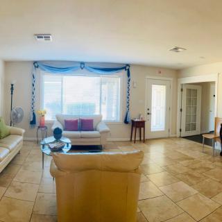 A spacious and well-lit living room with sofas, a coffee table, and large windows.