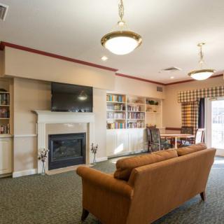 A cozy living room with a fireplace, television, and bookshelf.
