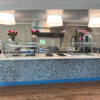 An empty modern cafeteria counter with stylish lighting and floral decorations.