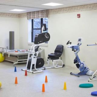 A physical therapy room equipped with various exercise machines and cones for rehabilitation exercises.