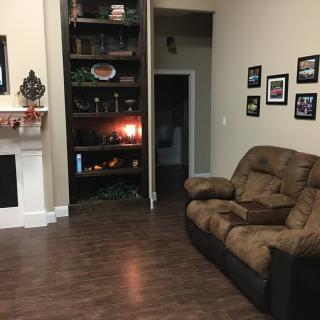A cozy living room with a brown sofa, fireplace, and decorative shelves.