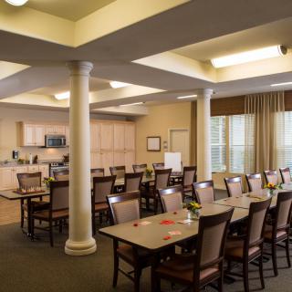 An organized meeting room with tables and chairs alongside a small kitchen area.