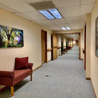 A long office corridor with doors on either side and artwork on the walls.