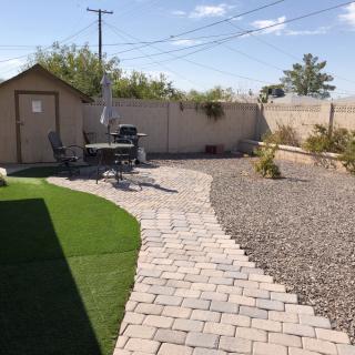 A well-maintained backyard featuring a paved walkway, gravel area, and a small lawn section.