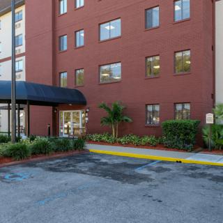 The exterior of a hotel building with a parking lot and entrance canopy.