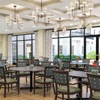 A spacious and well-lit dining area with modern chandeliers, featuring tables and chairs arranged neatly.