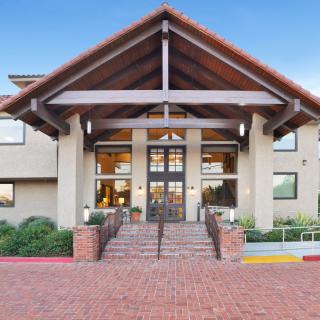 A modern building entrance with brick stairs and a peaked roof.