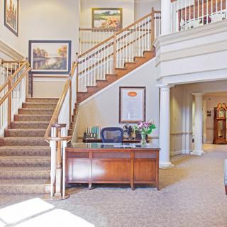 A well-lit lobby featuring a grand staircase and a reception desk.