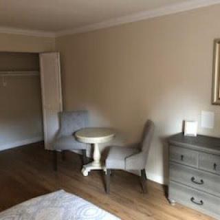A minimalist hotel room with two chairs, a small table, and a dresser.