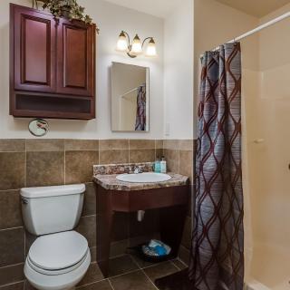 A compact bathroom featuring a toilet, sink with cabinet, mirror, and a shower with a curtain.