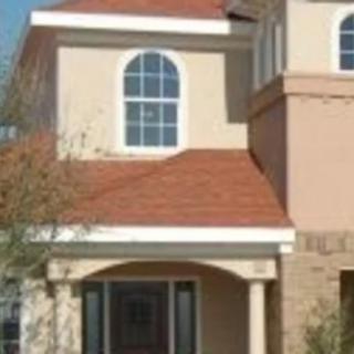 A modern two-story house with a red roof and arched windows.