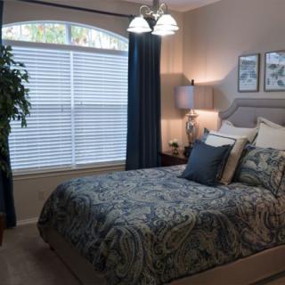 A cozy bedroom with a neatly made bed, large window, and elegant decor.