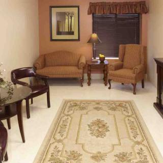 A cozy living room with a sofa, chairs, table, and a patterned rug.