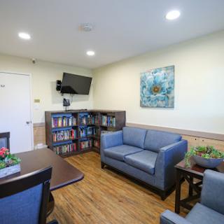 A cozy and inviting lounge area featuring comfortable seating, a bookshelf, and a television.