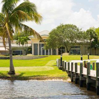 A scenic view of a waterfront building surrounded by palm trees and a dock.