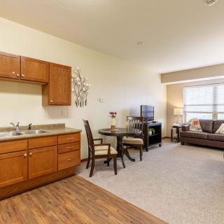 A cozy apartment with an open living room and kitchenette, featuring dining furniture and a comfortable seating area.