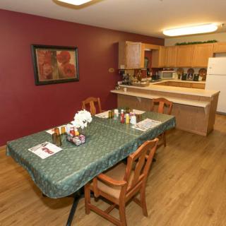 A cozy dining area connected to a kitchen with a table set for meals and warm decor.