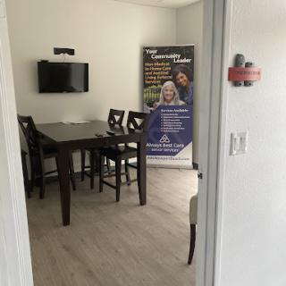 A view of a modern dining area with a table and chairs, featuring a television on the wall and an informational banner.
