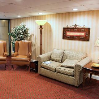 A cozy waiting room with a sofa, armchairs, and warm lighting.