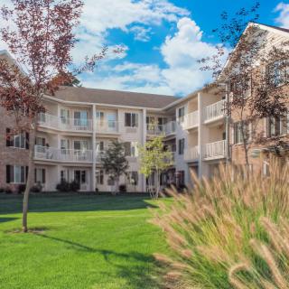 A residential apartment building with balconies and a well-maintained lawn.