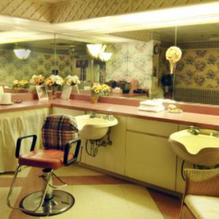 A vintage salon interior with retro styling, featuring pink and yellow colors, mirrors, and floral decorations.