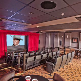 A cozy theater room with seating and a large movie screen displaying an image.