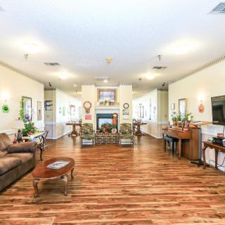 Spacious living room featuring a wooden floor, comfortable seating, a piano, and a fireplace.