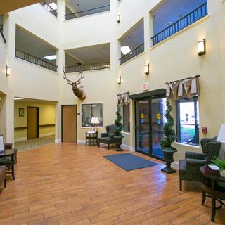 A spacious lobby area with seating, decorative elements, and a mounted animal head on the wall.