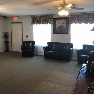 A cozy living room with dark leather furniture and a ceiling fan.