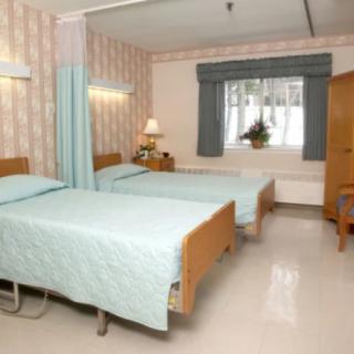 A hospital room with two patient beds and medical equipment.