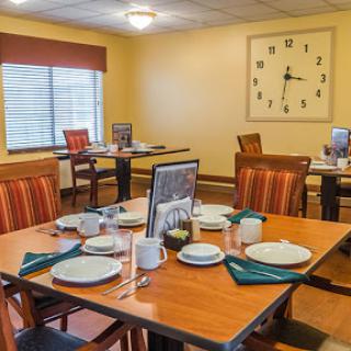 A cozy dining area set up for a meal, featuring wooden tables and chairs, complete with place settings and decorative elements.