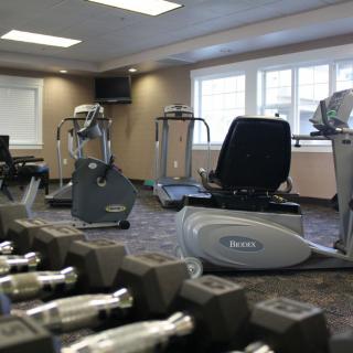 A well-equipped gym with various exercise machines and dumbbells.