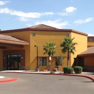 A building with palm trees in front, under a clear sky.
