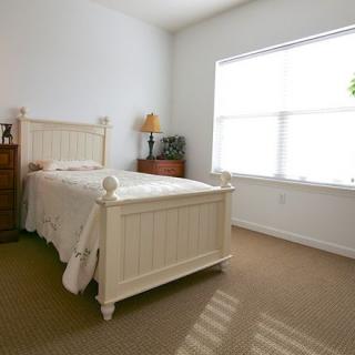 A minimalist bedroom with a single bed and large window letting in natural light.