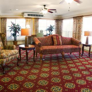 A cozy living room with patterned carpet, a sofa, and an armchair.