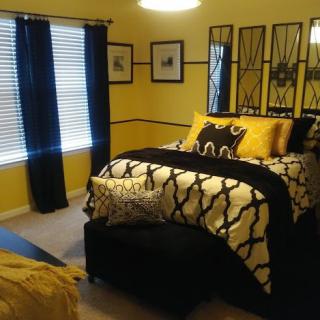 A stylish bedroom featuring yellow walls, black and white bedding, and coordinated decor.