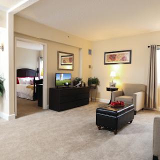 A cozy living room featuring comfortable furniture, a television, and light-colored decor.