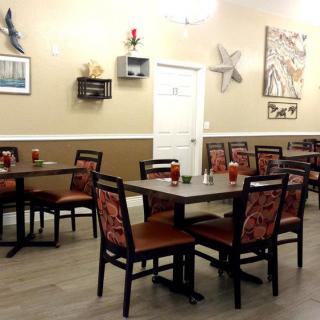An empty restaurant interior with neatly arranged tables and chairs, adorned with wall art and decorations.