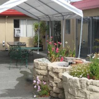 A cozy outdoor patio area with a white awning, garden, and stone planter.