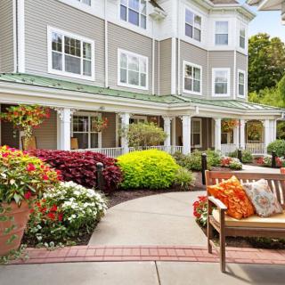 Beautifully landscaped garden area with a bench in front of a residential building.