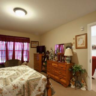 A cozy bedroom with a bed, dresser, television, and patterned curtains.