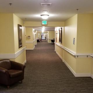 A well-lit hallway with chairs along the sides, featuring a neutral color scheme.
