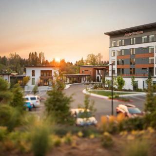 A scenic view of a hotel at sunset with cars in the parking lot.