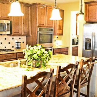 A modern kitchen with wooden cabinets, granite countertops, and an island with seating.
