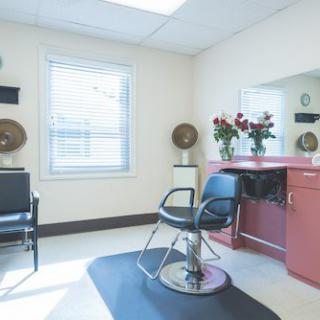 A well-lit hair salon interior with a styling chair and flowers on the counter.